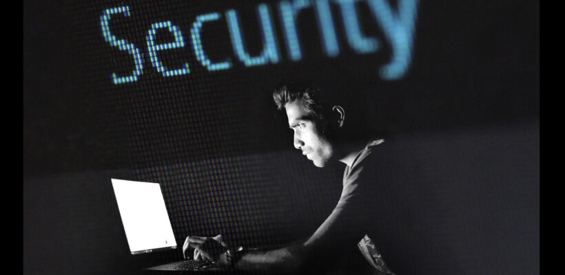 A man sitting at his laptop in front of the word security.