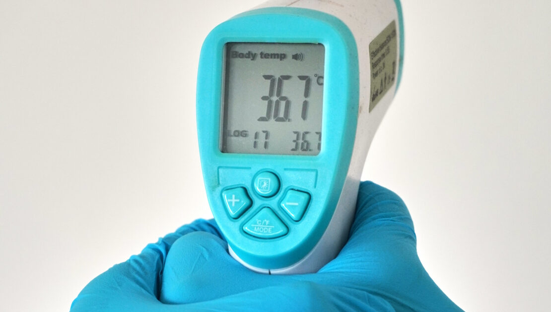 A person holding an electronic thermometer in their hand.